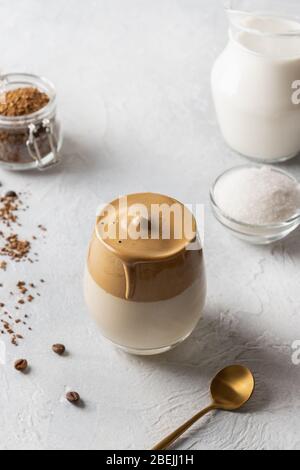 Hausgemachter Dalgona Kaffee im Glas mit Zutaten. Rezept Koreanisch trinken Latte mit Schaum von Instant-Kaffee. Vertikale Aufnahme. Kreierte neues Getränk während Quar Stockfoto