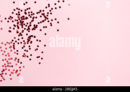 Rahmen aus glänzenden roten Sternen auf rosa Pastell Hintergrund. Monochromatisches Konzept. Stockfoto