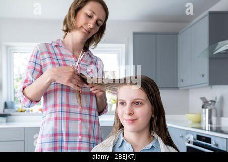 Mutter Schneiden Teenage Töchter Haare Zu Hause Während Lockdown Stockfoto