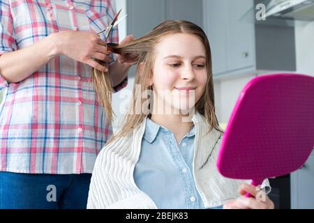 Mutter Schneiden Teenage Töchter Haare Zu Hause Während Lockdown Stockfoto