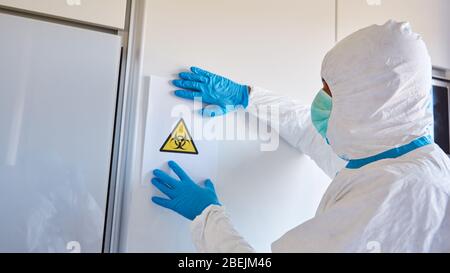 Das Personal der Krankheitskontrolle befestigte eine Warnung vor Biogefährdung an der Wand in einer Intensivstation einer Klinik mit Covid-19-Patienten Stockfoto