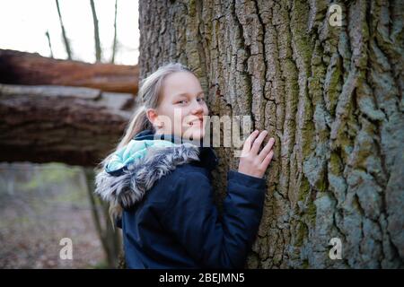 Ein Mädchen lehnt sich an den Stamm eines riesigen Baumes Stockfoto
