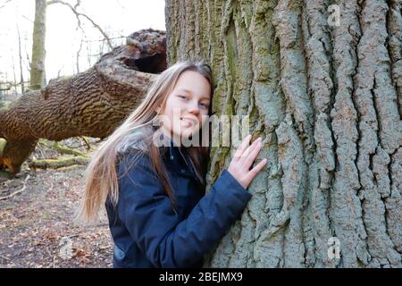 Ein Mädchen lehnt sich an den Stamm eines riesigen Baumes Stockfoto