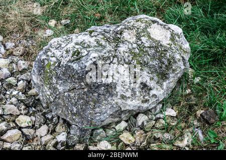 Großer alter Stein, der auf kleinen Steinen und auf dem grünen Gras liegt Stockfoto