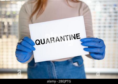 Quarantänezeichen in den Händen der Frau. Weiblich hält das Schild gegen das geschlossene Geschäft oder das Schaufenster Stockfoto