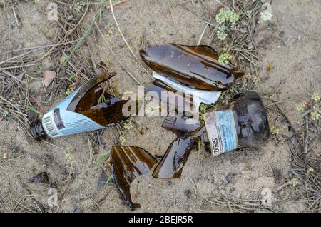 Odessa, Ukraine - 9. April 2020: Gebrochene Bierflasche im Sand. Eine Flasche leichtes Bier Robert Doms nach der Open-Air-Party. Blick von oben. Selecti Stockfoto