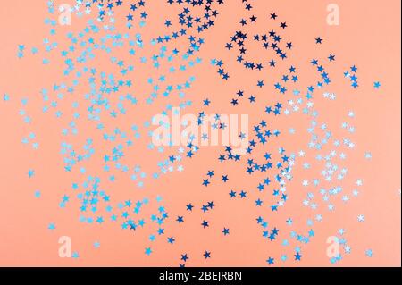 Zarter oranger Hintergrund mit blau glitzernden Sternen. Stockfoto