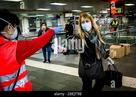 Barcelona, Katalonien, Spanien. 14. Apr 2020 - EIN Freiwilliger des Roten Kreuzes verteilt Schutzmaske unter Pendlern am Bahnhof Catalunya in Barcelona. Tausende von Menschen kehren zur Arbeit zurück, nachdem die spanische Regierung die strengsten Maßnahmen der Coronavirus-Haft aufzuheben hat. Quelle: Jordi Boixareu/Alamy Live News Stockfoto