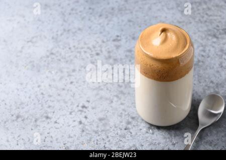 Dalgona schaumig Kaffee in Glas auf grau. Trend koreanischen Drink Latte mit Schaum von Instant-Kaffee. Nahaufnahme. Kopierbereich. Stockfoto