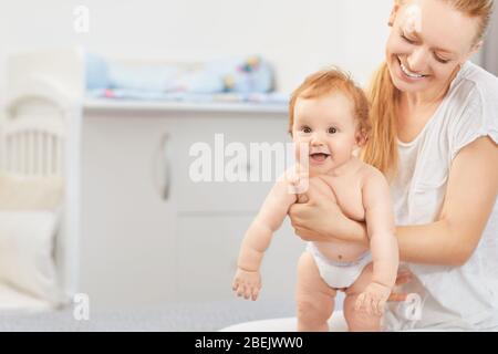 Mutter umarmte ihr Baby auf einem Bett Stockfoto
