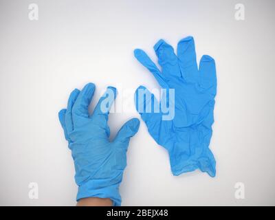 April 2020, Hand trägt EINEN blauen Einweg-Handschuh, der einen anderen blauen Einweg-Handschuh aufgreift, London, Großbritannien Stockfoto