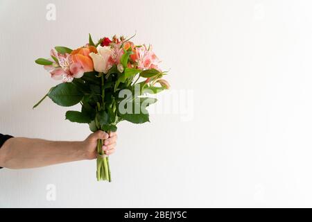 Blumenstrauß mit schönen Blumen in Mannen Hand auf weißem Hintergrund. Stockfoto