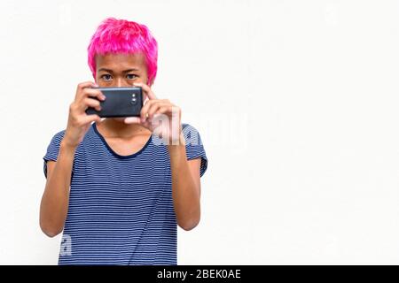 Junge rebellische asiatische Frau mit rosa Haar, die mit Telefon fotografieren Stockfoto