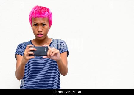 Junge rebellische asiatische Frau mit rosa Haar, die mit Telefon fotografieren Stockfoto