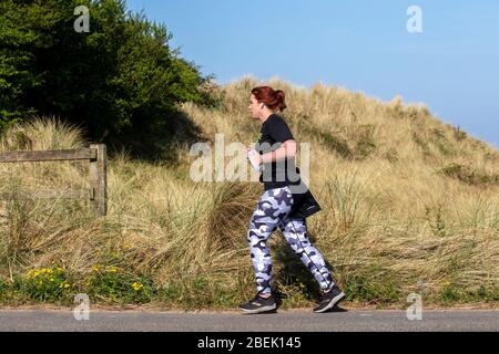 Southport, Merseyside, Großbritannien. April 2020. UK Coronavirus: Die Einheimischen nehmen an einem sonnigen Frühlingstag an der Strandpromenade mit Blick auf das Naturschutzgebiet Ribble Estuary leichte Übungen, während England seine vierte Woche in der Absperrung beginnt. Quelle: MediaWorldImages/AlamyLiveNews Stockfoto