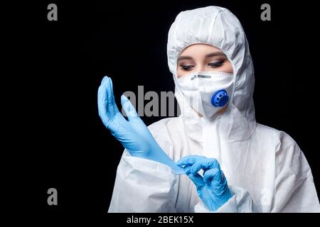 Die Ärztin im Schutzanzug und Maske Atemschutzmaske in schwarzem Hintergrund. Konzept Covid-19 Pandemie Stockfoto