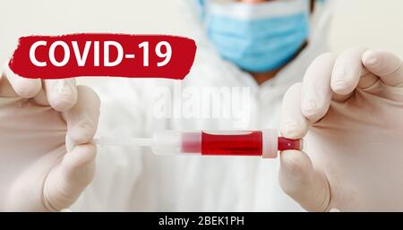 Text covid-19 auf rotem Warnschild. Coronavirus Blutprobe in den Händen der Ärzte. Doktor in Maske auf weißem Hintergrund. Konzept der Medizin Labor Gesundheit Stockfoto