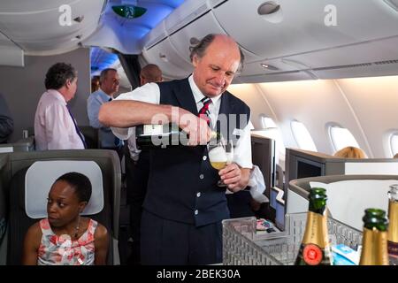 Johannesburg, Südafrika - 06. Februar 2014: Männliche Kabinencrew gießt ein Glas Champagner in der Business-Klasse eines Airbus A380 Stockfoto