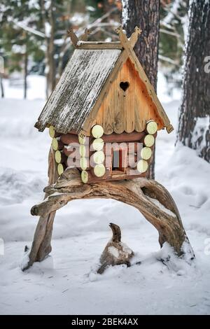 Vogelhaus aus Holz. Handgefertigte Blockhütte Vogelhaus auf Haken Baum im verschneiten Wald montiert Stockfoto