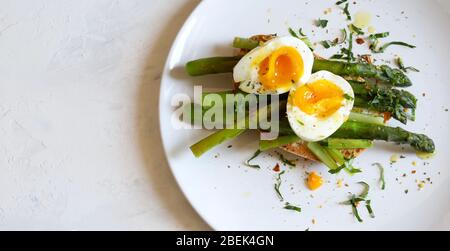 Frühstück Food Konzept.Tasty Toast mit Spargel, pochiertes Ei und Gewürz auf Teller auf weißem Hintergrund serviert. Draufsicht, Kopierbereich. Gesunde Ernährung. Stockfoto