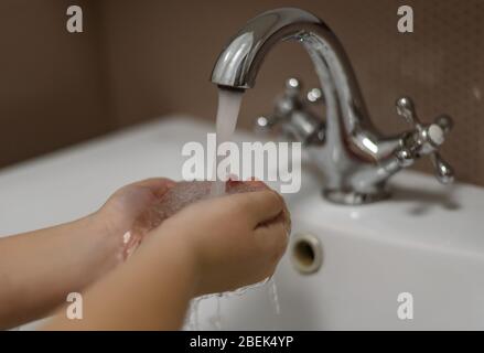 Waschen der Kinderhände unter dem Kran mit Wasser. Stockfoto