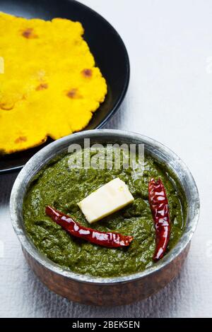 Köstliche Schale Sarso ka saag mit Makki KI Roti auf einem Tisch gehalten. Stockfoto