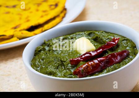 Köstliche Schale Sarso ka saag mit Makki KI Roti auf einem Tisch gehalten. Stockfoto