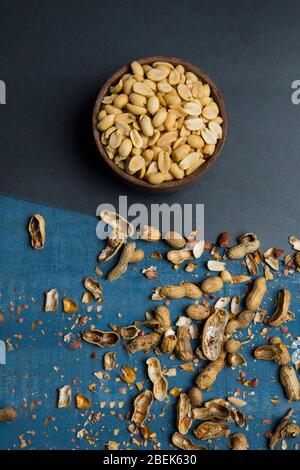 Einfache Erdnüsse in einer Holzschale zusammen mit rissigen Muscheln aufbewahrt. Stockfoto