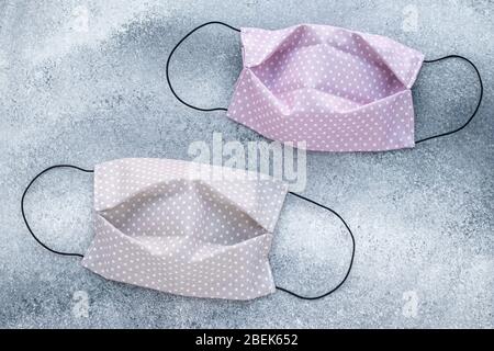 Wiederverwendbare Polka Dot Schutzmaske auf grauem Grund. Zwei handgefertigte Masken aus Textil in Erbsen. Frauenmode-Konzept. Schutz vor vi Stockfoto