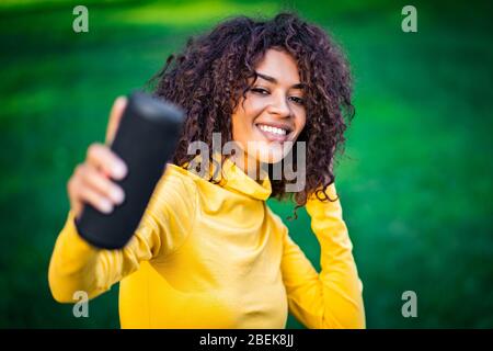 Moderne trendy afroamerikanischen Mädchen hören Musik von drahtlosen tragbaren speaker.Young schöne Frau genießen, tanzen im Park. Stockfoto