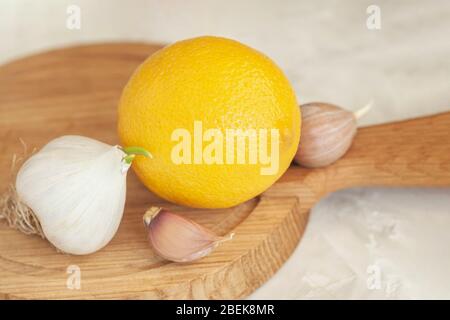 Kopf von Knoblauch mit Scheiben und Zitrone auf Holzbrett Nahaufnahme, Volksheilmittel gegen Grippe und Erkältungen, Konzept der natürlichen Vitamine, Immunität und Stockfoto