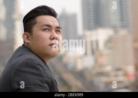 Nahaufnahme Profil Blick auf junge übergewichtige asiatische Geschäftsmann Denken in der Stadt Stockfoto