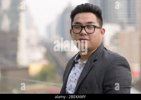 Junge übergewichtige asiatische Geschäftsmann trägt Brillen in der Stadt Stockfoto