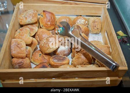 Verschiedene Brotsorten in einer Holzkiste am Frühstücksbuffet. Hotel Offenes Buffet Brot . Gebäck und Knoblauchbrot in einer Holzkiste und Greifer serviert Stockfoto