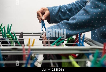 Nahaufnahme eines Menschen, der seine frisch gewaschene Kleidung aufhängt Stockfoto