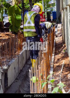 SINGAPUR – 3. MÄRZ 2020 – Bauarbeiter in gut sichtbarer Schutzausrüstung arbeiten an einem Abfluss auf einem Baustelle in Singapur Stockfoto