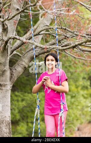 Outdoor-Porträt eines jungen Mädchens auf einer Schaukel im Frühling Stockfoto
