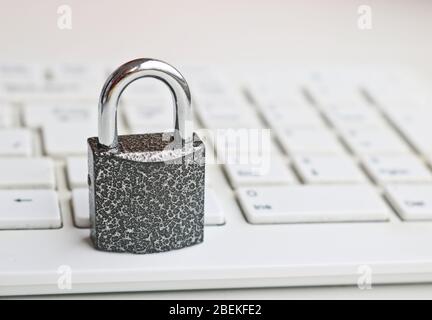 Selektiver Fokus geschlossenes Vorhängeschloss auf einer weißen Tastatur. Cybersicherheitskonzept. Sicherheitssperre Stockfoto