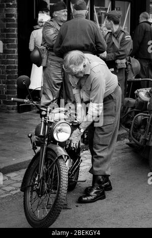 Schwarz-Weiß Nahaufnahme von Senior Mann in Vintage Uniform mit Vintage Motorrad, Motorrad bei 1940s Krieg Sommer Veranstaltung, Black Country Museum, Großbritannien. Stockfoto