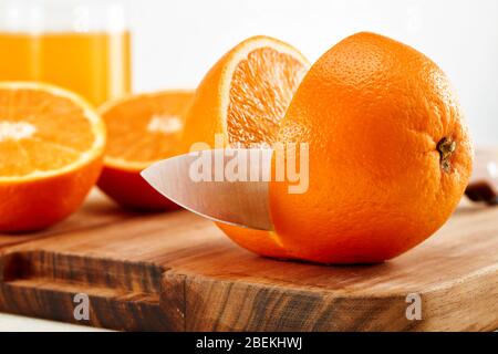 Messer schneiden orange auf Holzschneidebrett. Orangensaft Zubereitung in der Küche. Stockfoto