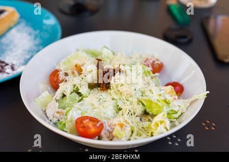 Caesar Salat mit Huhn, Tomaten, Salat und Parmesan. Salat in einem weißen Teller Stockfoto