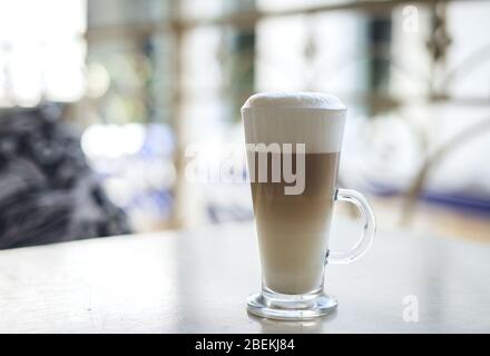 Glas Latte mit Zucker auf weißem Teller. Stockfoto