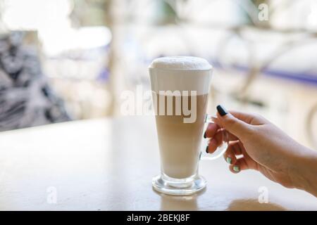 Die Hand der Frau hält ein Glas Latte Stockfoto