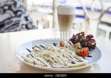 Crepes mit Hähnchen, Tomaten und Glas heißen Latte Stockfoto