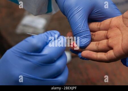 Ein Gesundheitsarbeiter, der Handschuhe trägt, nimmt Blutproben von einem Mann, der vor kurzem eine Reisegeschichte außerhalb des Landes im provisorischen Schnelltestzentrum für Coronavirus (COVID-19) in Lalitpur hat.Nepal hat bisher 12,609 Tests für COVID-19 durchgeführt und von ihnen wurden 16 Fälle bestätigt. Stockfoto