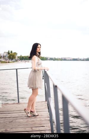 Mädchen ist am See gekleidet. Junge Frau in grauem Sommerkleid Stockfoto