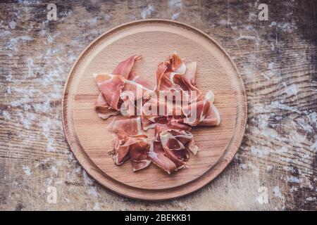 Prosciutto auf einem Holzteller. Fleischschnitt auf einem Holzbrett Stockfoto