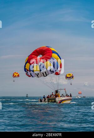 Vertikale Ansicht von Menschen Parasailing von einem Schnellboot in Bali, Indonesien. Stockfoto