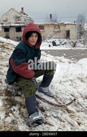 Sarajevo 1995 - Kind spielt im Schnee in Wohngebiet, das von serbischen Bombenangriffen während der Belagerung von Sarajevo, Bosnien und Herzegowina getroffen wurde Stockfoto