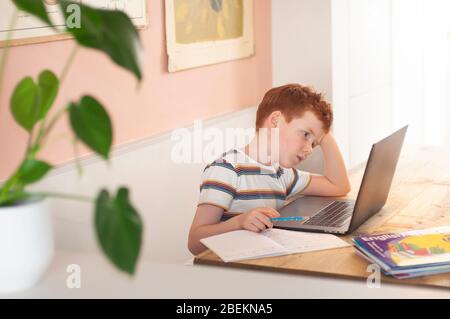 Junge vor dem Teenager, der sich auf seine Schularbeit am Laptop zu Hause konzentriert Stockfoto